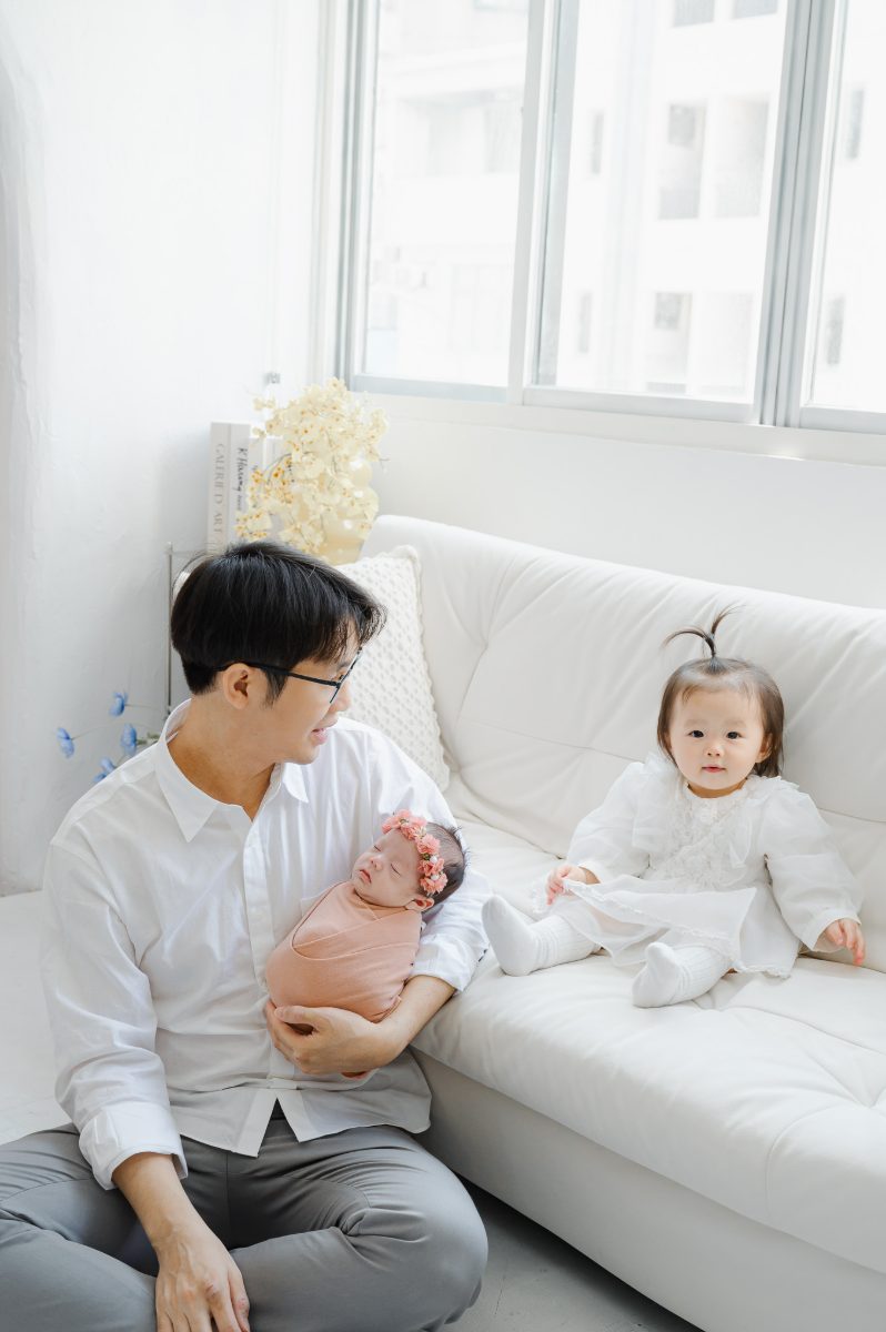 台中親子寫真：爸爸抱著新生兒與沙發上的姊姊